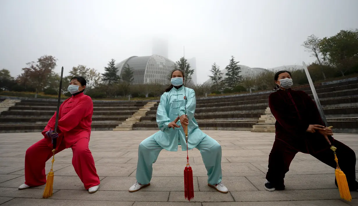 Sejumlah wanita mengunakan masker saat melakukan latihan bela diri pada pagi hari di Jinan, Provinsi Shandong, China, (10/11). Selama lima hari ini Cina mengalami kualitas udara yang menurun karena tercemar polusi. (REUTERS/Stringer)