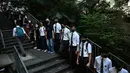 Para siswa, alumni dan guru saling memegang tangan di area Mid-Levels, Hong Kong, Senin (9/9/2019). Aksi dilakukan para siswa yang masih berseragam sekolah sambil memakai masker sebagai bentuk dukungan terhadap demonstran anti pemerintah setelah bentrokan pada akhir pekan. (Anthony WALLACE/AFP)