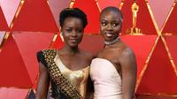 Aktris Kenya, Lupita Nyong'o dan aktris AS, Danai Gurira berpose untuk fotografer di karpet merah ajang Piala Oscar 2018, Los Angeles, Minggu (4/3).  Dua pemain "Black Panther" tersebut adu cantik mengenakan gaun seksi dan elegan. (ANGELA WEISS / AFP)