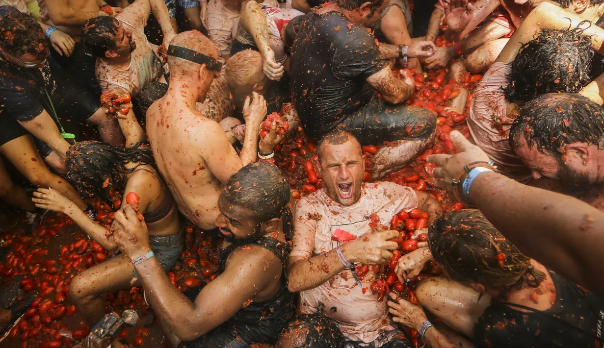 Orang-orang yang bersuka ria saling melempar tomat dalam acara tahunan "Tomatina", pesta pertarungan tomat di desa Bunol dekat Valencia, Spanyol, Rabu (31/8/2022). Pertarungan tomat terjadi sekali lagi setelah penangguhan selama dua tahun karena pandemi virus corona covid-19. (AP Photo/Alberto Saiz)