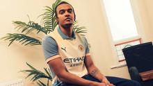Bek Manchester City, Manuel Akanji, berpose dengan jersey "Definitely City", seragam yang terinspirasi dari sampul album Definitely Maybe milik Oasis. Jersey ini juga didesain oleh salah seorang personel Oasis, Noel Gallagher. (Sumber foto: Web resmi Manchester City)