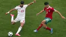 Aksi pemain Iran, Ramin Rezaeian (kiri) melepaskan tembakan saat diadang pemain Maroko, Achraf Hakimi (kanan) pada laga grup B Piala Dunia 2018 di St. Petersburg Stadium, Rusia, (15/6/2018). Iran menang 1-0. (AP/Darko Vojinovic)