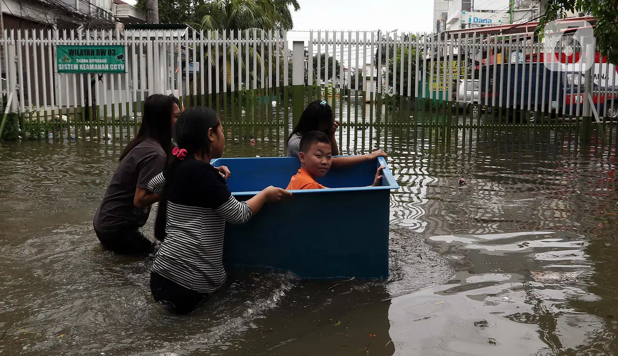 Warga melintasi banjir yang merendam kawasan Green Garden, Jakarta Barat, Selasa (25/2/2020). Hujan yang mengguyur kawasan Jakarta membuat kawasan tersebut tergenang banjir setinggi 60-80 cm. (Liputan6.com/Johan Tallo)