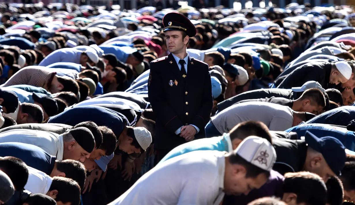 Seorang polisi berdiri di antara ratusan muslim Rusia yang tengah melaksanakan salat Idul Fitri di luar masjid di pusat kota Moskow, Selasa (5/7). Perayaan Idul Fitri 1437 H di Rusia jatuh pada hari ini. (Kirill KUDRYAVTSEV/AFP)