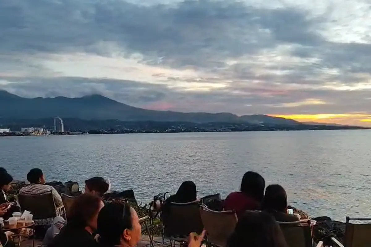 Warga duduk duduk menikmati matahari terbenam di kawasan Megamas, Manado.