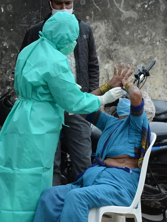 Seorang petugas kesehatan mengumpulkan sampel usap dari seorang wanita untuk menguji virus Covid-19 di daerah kumuh di Hyderabad (23/9/2020). Infeksi virus corona di India kembali melonjak pada Rabu (23/9) setelah sehari sebelumnya menyentuh angka terendah dalam hampir sebulan. (AFP/Noah Seelam)