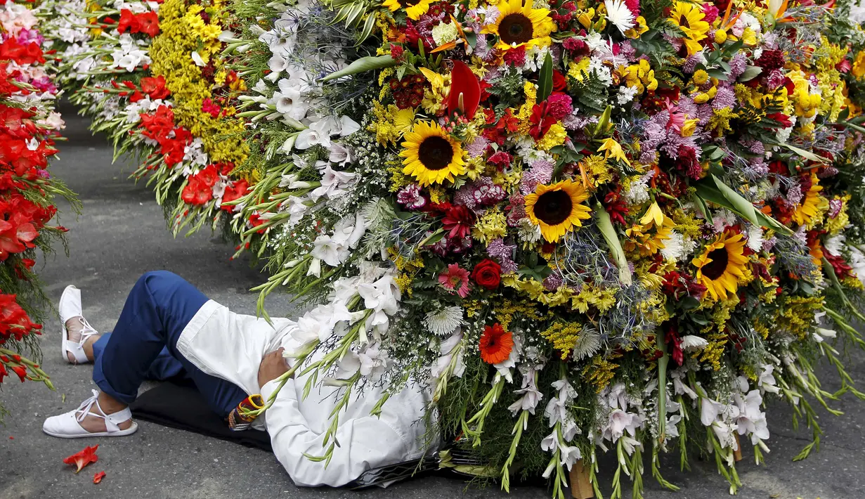 Warga beristirahat dibawah rangkaian bunga saat digelarnya festival bunga tahunan di Medellin, Kolombia, Minggu (9/8/2015). Festival yang dikenal dengan nama Silleteros Parade ini telah dilangsungkan sejak 1957. (REUTERS/Fredy Builes)