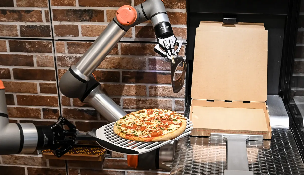 Foto yang diambil pada 1 Juli 2021 menunjukkan "Pazzi", robot pembuat pizza yang sedang bekerja di sebuah restoran di Paris. Robot pembuat pizza dari startup Paris Pazzi tersebut mulai beroperasi di jantung kota Paris pada 5 Juli 2021 (BERTRAND GUAY/AFP)