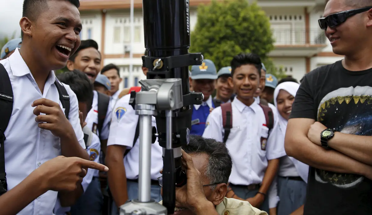Anggota Hongkong Astronomical Society, Wayne Fong (kanan), mendampingi seorang guru menggunakan teropong di sebuah sekolah di Ternate, (7/3). Ribuan wisatawan penggemar astronomi mendatangi sejumlah titik pengamatan GMT di Indonesia. (REUTERS/Beawiharta)