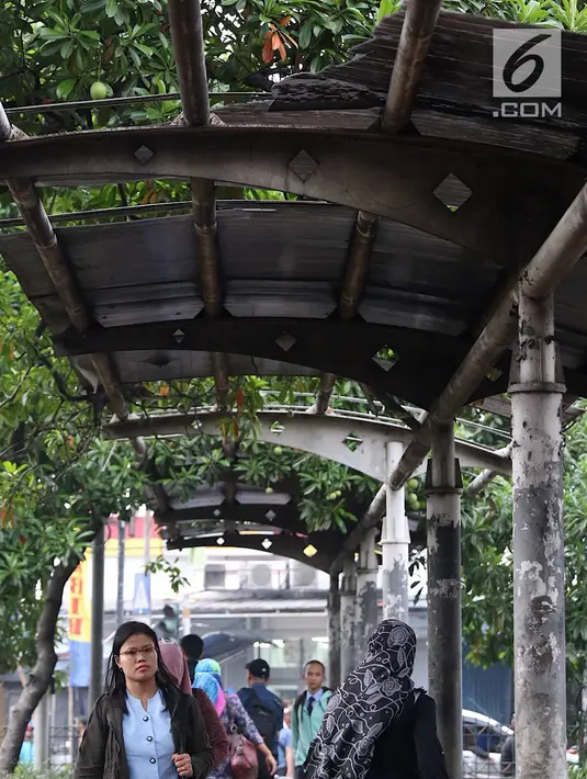 Warga melintasi jalur khusus pejalan kaki di kawasan Kampung Rambutan, Jakarta, Selasa (19/2). Atap rusak yang juga tidak dilengkapi dengan lampu penerangan mengganggu kenyamanan pejalan kaki. (Liputan6.com/Immanuel Antonius)