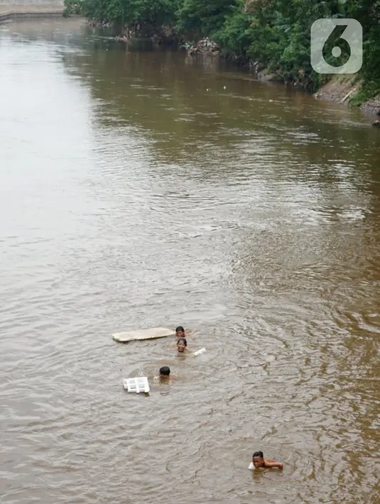 Anak-anak berenang di aliran Sungai Ciliwung, Jatinegara, Jakarta Timur, Sabtu (4/7/2020). Minimnya lahan bermain menyebabkan anak-anak tersebut bermain tidak pada tempatnya, meski dapat membahayakan keselamatan. (Liputan6.com/Immanuel Antonius)