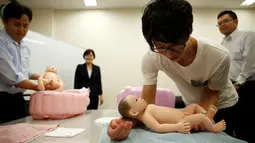 Seorang pria belajar meletakkan bayi saat mengikuti "Ikumen", Tokyo, Jepang, Senin (18/9). Kursus ini memberikan pengajaran cara mengasuh bayi yang benar kepada kaum pria. (REUTERS/Issei Kato)