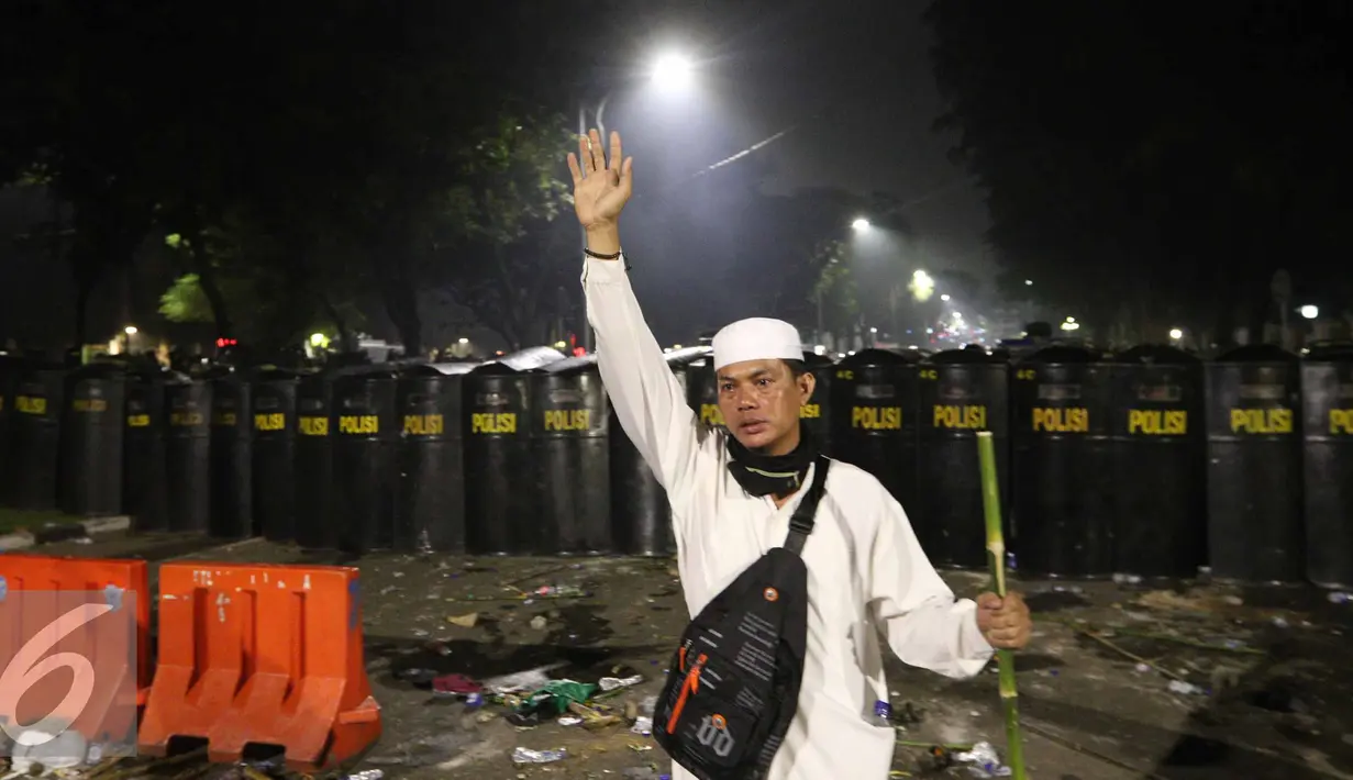 Seorang pendemo mencegah kawannya untuk menyerang polisi saat Aksi Damai 4 November, Jakarta, Jumat (4/11). Bentrok terjadi usai polisi membubarkan paksa dengan gas air mata. (Liputan6.com/Faizal Fanani)