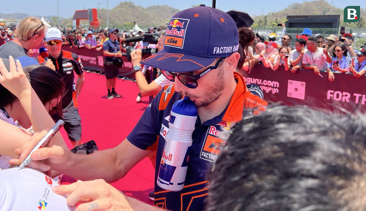 Pembalap Red Bull KTM, Jack Miller, memberikan tanda tangan kepada salah satu penggemar dalam kegiatan MotoGP Hero Walk di Sirkuit Mandalika, Lombok , Minggu (15/10/2023). (Bola.com/Benediktus Gerendo Pradigdo)