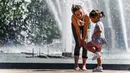 Orang-orang menikmati musim semi yang panas dengan bermain dekat air mancur di Moskow, Rusia, Selasa (18/5/2021). Suhu di Moskow telah mencapai 31 derajat Celcius. (Alexander NEMENOV/AFP)