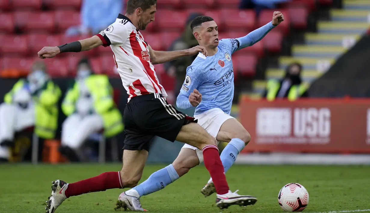 Gelandang Manchester City, Phil Foden, berebut bola dengan bek Sheffield United, Chris Basham, pada laga lanjutan Liga Inggris di Stadion Bramall Lane, Sabtu (31/10/2020) malam WIB. Manchester City menang 1-0 atas Sheffield.  (Tim Keeton/Pool via AP)