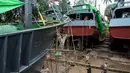 Para pekerja berjalan melewati kapal-kapal yang sedang diperbaiki di galangan kapal di tepi Sungai Yangon, yang terletak di pinggiran Yangon, Myanmar (30/7/2019). (AFP Phot/Sai Aung Main)