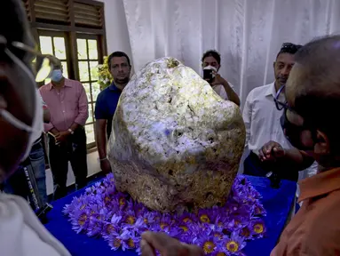 Orang-orang melihat permata yang diklaim sebagai safir biru korundum alami terbesar di dunia Bernama 'Queen of Asia', di Horana, sekitar 45 km dari Kolombo, Sri Lanka pada 12 Desember 2021. Beratnya 310 kg, ditemukan di lubang pencarian permata sekitar tiga bulan lalu. (Ishara S. KODIKARA / AFP)