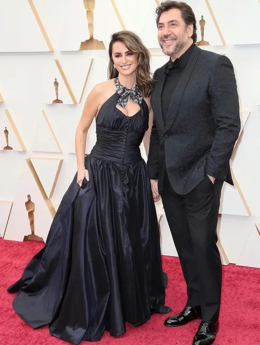 Pasangan Penelope Cruz & Javier Bardem kompak dengan busana all black di Oscar 2022. Penelope kenakan gaun glamor dari Chanel, sementara Javier mengenakan tuxedo hitam. (Instagram/fashionbombdaily).