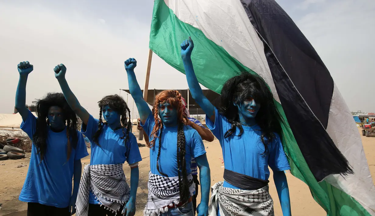Warga Palestina bergaya seperti karakter dari film "Avatar" mengibarkan bendera selama protes menuntut hak untuk kembali ke kampung halaman mereka di perbatasan Israel-Gaza, Timur Khan Yunis di Gaza selatan Strip, (4/5). (AFP Photo/Said Khatib)
