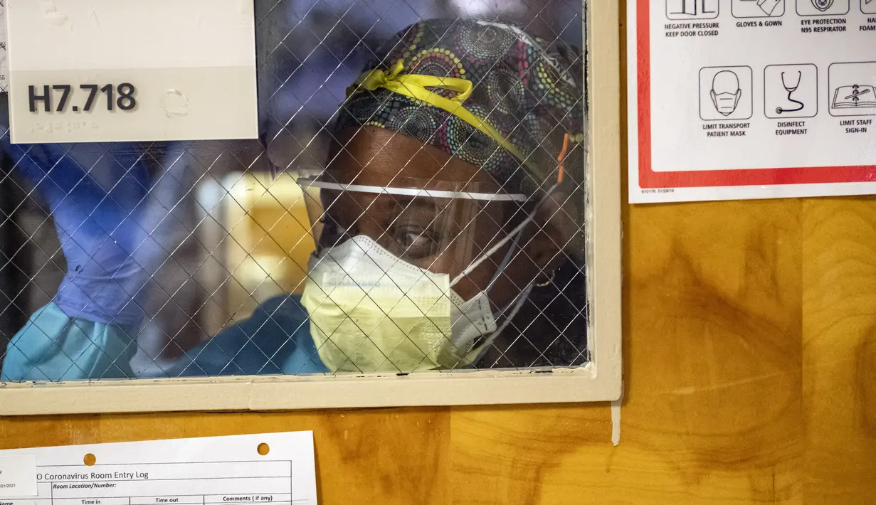 Petugas melalui jendela ruang tekanan negatif dengan pasien Covid-19, meminta pasokan medis di bangsal ICU UMass Memorial Medical Center di Worcester, Massachusetts, Selasa (4/1/2022). Rumah sakit mengklaim mereka dipenuhi pasien dan tidak memiliki banyak tempat tidur tersisa. (Joseph Prezioso/AFP)
