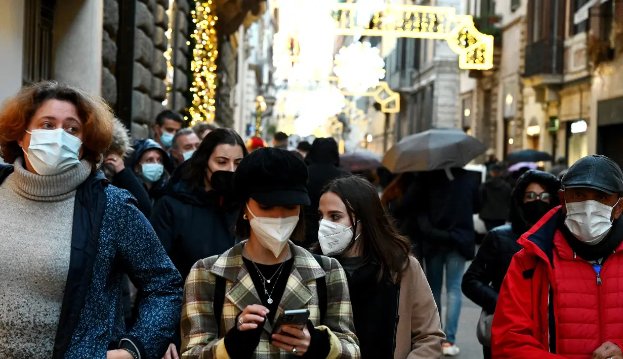 Orang-orang memakai masker di sepanjang jalan perbelanjaan mewah Via Condotti di pusat kota Roma, Italia, Minggu (5/12/2021). Kota Roma memberlakukan kewajiban penggunaan masker di ruang terbuka pusat kota dan area perbelanjaan sibuk lainnya hingga 31 Desember mendatang. (Vincenzo PINTO/AFP)