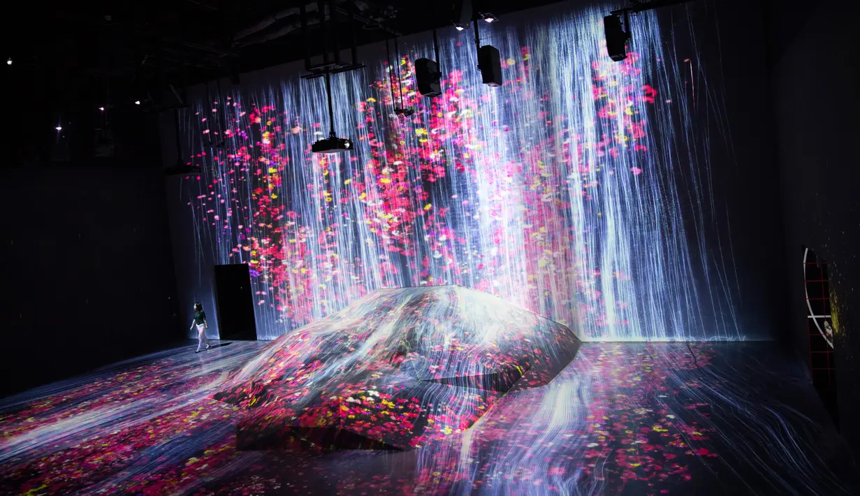 Anggota Teamlab Jepang berjalan di ruang instalasi digital air terjun di Mori Building Digital Museum Seni, Tokyo, Jepang (1/5). Seni digital air terjun yang dipenuhi bunga ini adalah karya tim kolektif Jepang. (AFP Photo/Behrouz Mehri)
