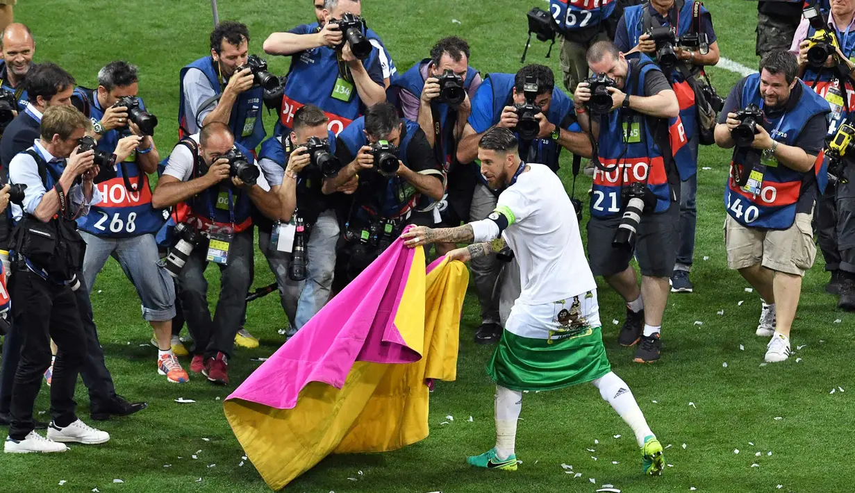 Sergio Ramos bergaya layaknya seorang Matador saat merayakan kemenangan Real Madrid merebut trofi Liga Champions di San Siro Stadium, Milan, (29/5/2016) WIB. Madrid menang lewat adu pinalti 5-3.  (AFP/Tiziana Fabi)