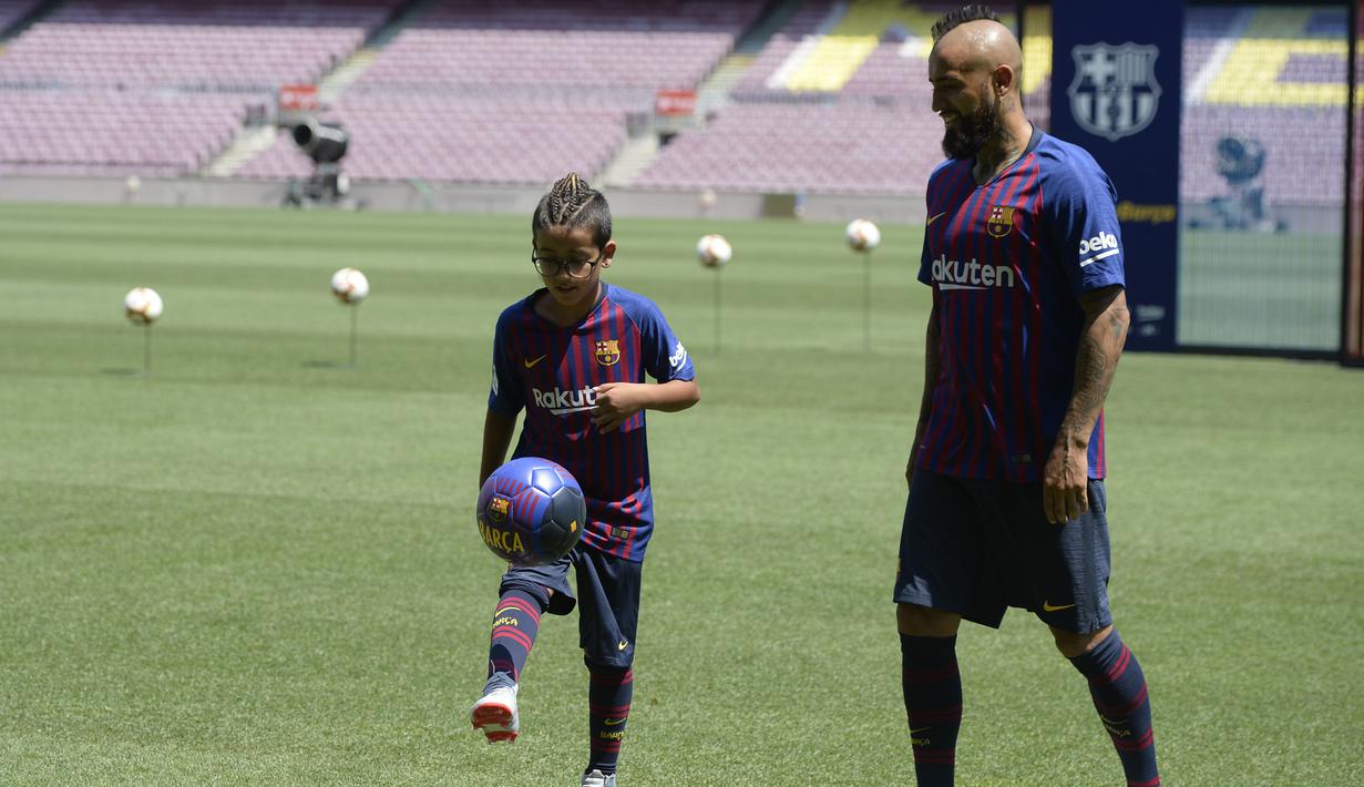 Pemain baru Barcelona, Arturo Vidal, bersama anaknya Alonso, saat perkenalan di Stadion Camp Nou, Senin, (7/8/2018). Barcelona merogoh kocek sebesar 19 juta euro untuk mengamankan jasa pria berkebangsaan Cile itu. (AFP/Josep Lago)