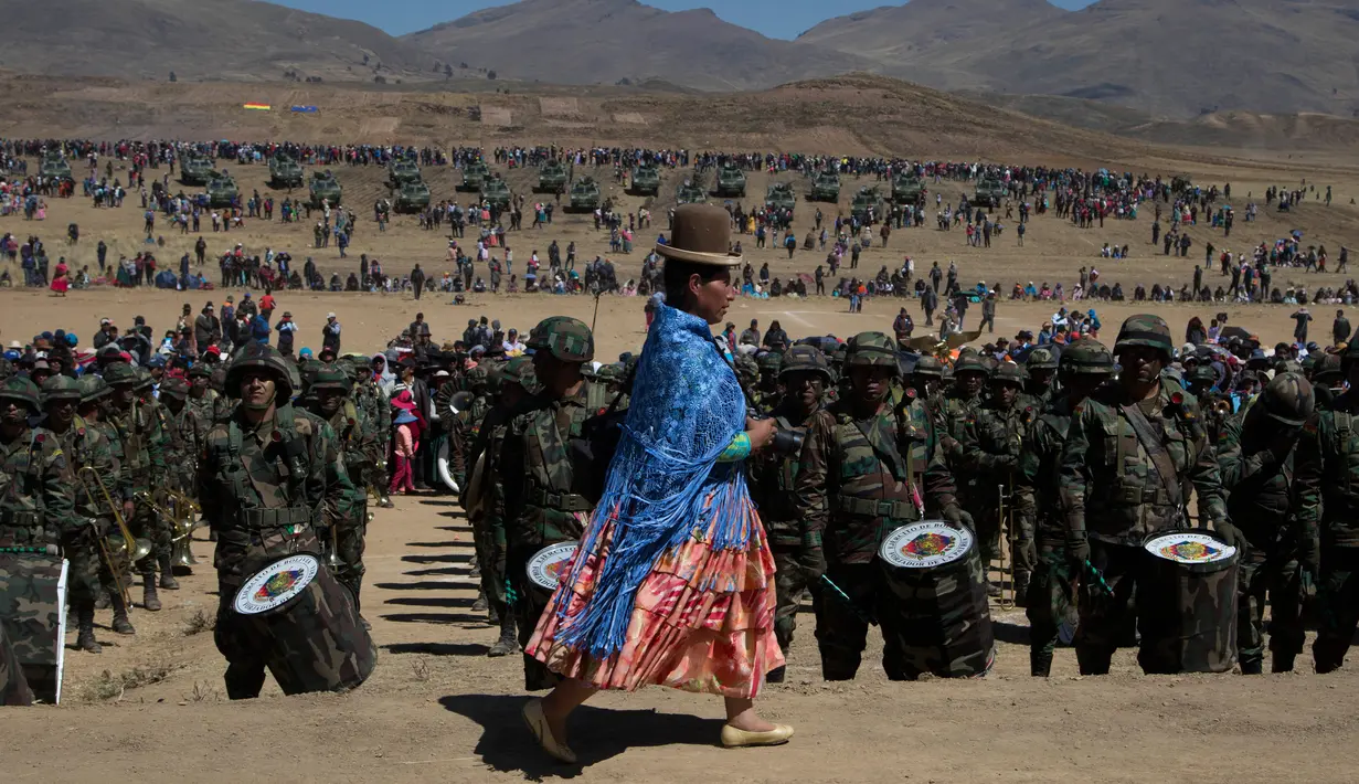 Seorang fotografer wanita pribumi suku Aymara melintas di depan barisan pasukan militer saat peringatan ulang tahun tentara Bolivia ke-192 di Kjasina, Bolivia (7/8). (AP Photo/Juan Karita)