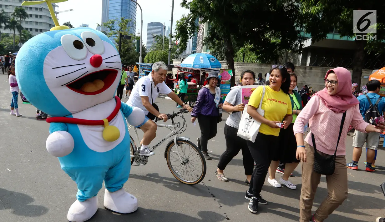 Seniman berkostum boneka Doraemon menggoda warga saat kegiatan Car Free Day di Bundaran HI di Jakarta, Minggu, (12/11). Kegiatan tersebut bermaksud untuk menghibur warga. (Liputan6.com/Fery Pradolo)