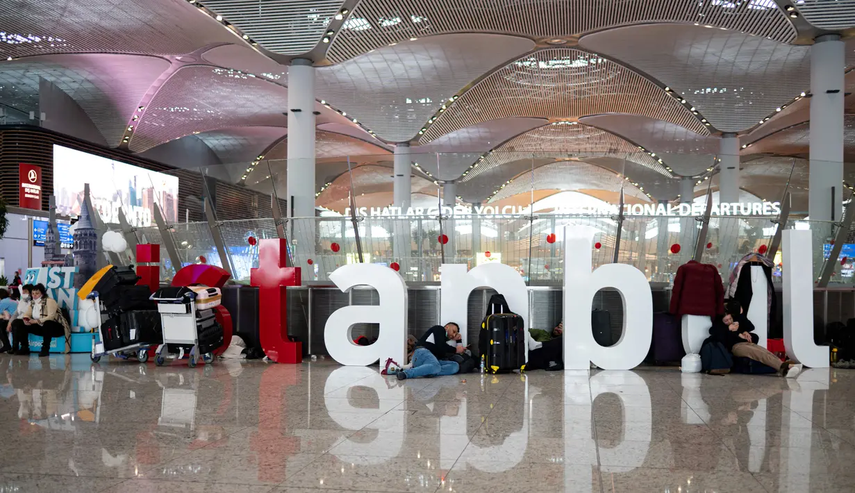 Penumpang yang terdampar menunggu di bandara Istanbul, di mana penerbangan dibatalkan karena badai salju dan hujan salju lebat, di Istanbul, Turki, pada 25 Januari 2022. Bandara Istanbul menunda pengoperasian kembali karena kondisi cuaca buruk yang menghambat operasional. (Yasin AKGUL/AFP)