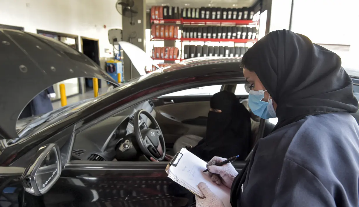 Mekanik wanita Saudi membuat catatan di sebelah kendaraan di bengkel perbaikan dan servis di Jeddah, Arab Saudi (27/12/2021). Wanita Arab Saudi kini mulai mendapat kesempatan bekerja di area yang sebelumnya dianggap hanya identik pria seperti di toko suku cadang mobil di Jeddah. (AFP/Amer Hilabi)