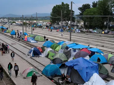 Sejumlah imigran saat membuka tenda di sebuah stasiun kereta api di sebuah kamp darurat bagi para migran dan pengungsi di perbatasan Yunani-Macedonia dekat desa Idomeni, Yunani, 10 Mei 2016. (REUTERS / Marko Djurica)