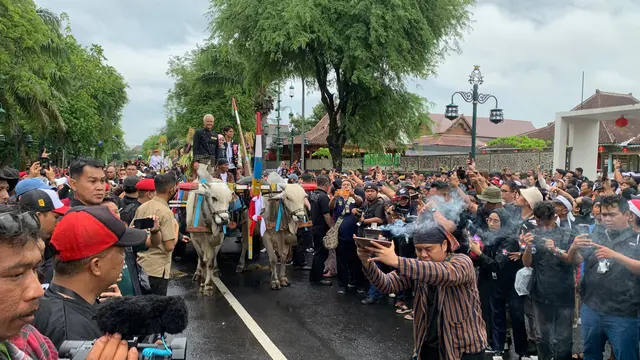Capres Ganjar Pranowo menaiki gerobak sapi di Solo, Jawa Tengah, Sabtu (2/10/2024).
