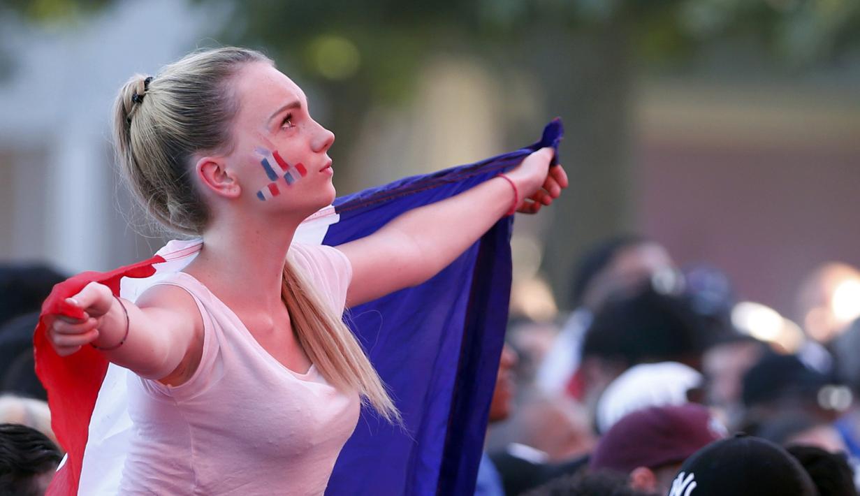 Aksi fans cantik Prancis dengan membentangkan bendera diareal fan zone saat timnya melawan Jerman pada semifinal piala Eropa 2016 di Paris, (7/7/2016). (REUTERS/Regis Duvignau)