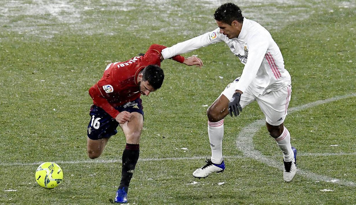 Pemain Osasuna, Jonathan Calleri, berebut dengan pemain Real Madrid, Raphael Varane, pada laga Liga Spanyol di Stadion El Sadar, Sabtu (9/1/2021). Kedua tim bermain imbang 0-0. (AP/Alvaro Barrientos)