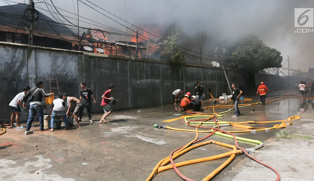 Petugas pemadam kebakaran bersana warga mencoba memadamkan api yang membakar pemukiman padat penduduk di kawasan Manggarai, Jakarta, Rabu (10/7/2019). Belum diketahui pasti penyebab api membakar pemukiman warga tersebut. (Kapanlagi.com/Budy Santoso)