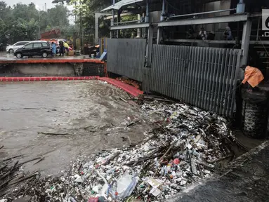 Seorang petugas membersihkan sampah yang menyangkut di Pintu Air Manggarai, Jakarta, Senin (5/2). Volume sampah terus meningkat lebih dari 200 ton. (Liputan6.com/Faizal Fanani)