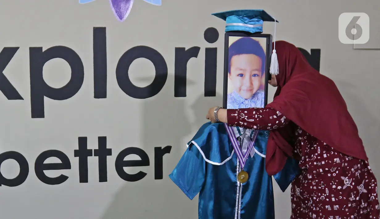 Kepala Sekolah mengalungkan piagam wisuda kepada siswa Kelompok Bermain Taman Kanak-kanak (KB TK) Sekolah Nasional Satu (Nassa School) di Bekasi, Rabu (1/07/2020). Sekolah itu menggunakan teknologi virtual dan roboda guna memudahkan prosesi wisuda di tengah Covid-19. (Liputan6.com/Herman Zakharia)