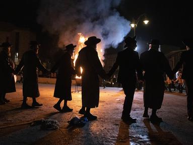 Pria Ultra-Ortodoks Yahudi menari di samping api unggun di Yerusalem, Kamis (29/4/2021). Selama liburan Lag Ba'Omer, menandai berakhirnya wabah yang dikatakan telah membinasakan orang Yahudi selama zaman Romawi. (AP Photo/Sebastian Scheiner)