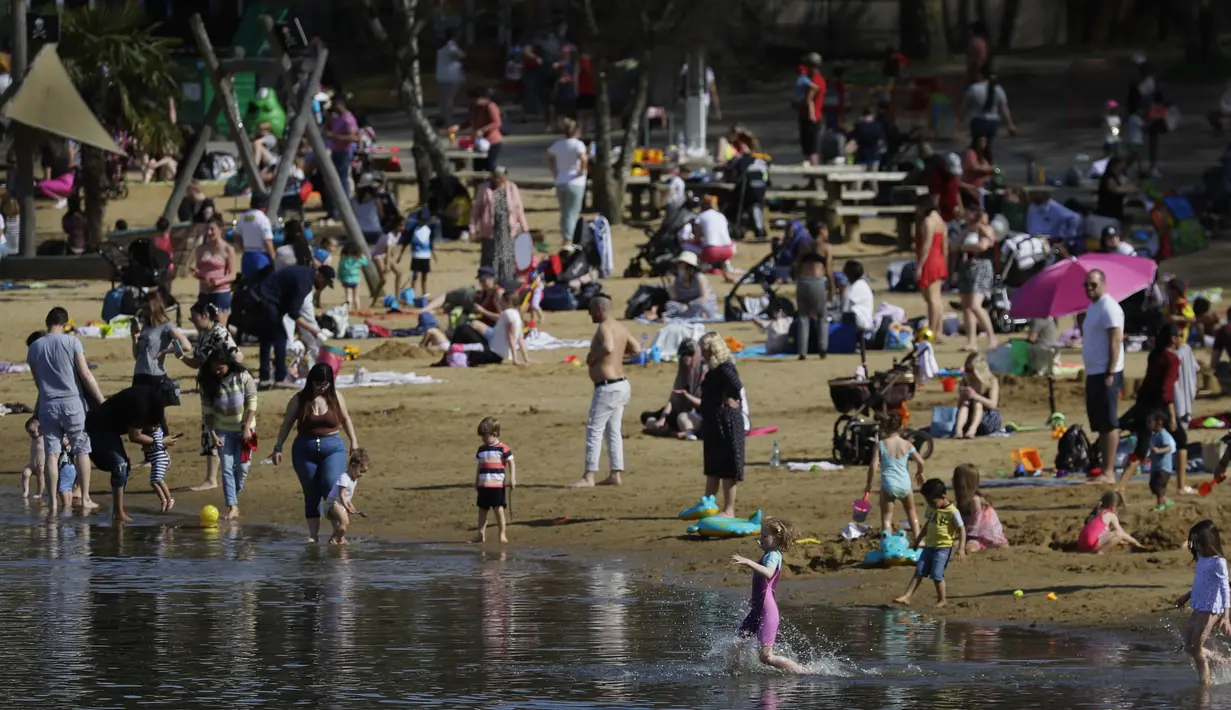 Orang-orang menikmati cuaca hangat di Ruislip Lido di London, Selasa (30/3/2021).  Suhu di beberapa bagian Inggris diperkirakan akan lebih hangat secara signifikan minggu ini karena keluarga dan teman berkumpul kembali dan kegiatan olahraga luar ruangan diizinkan untuk dilanjutkan di Inggris. (AP Ph