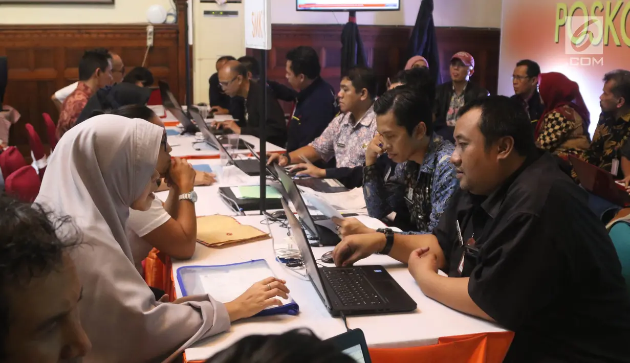 Petugas melayani orang tua murid tingkat SMA/SMK di Posko Pelayanan Peneriman Peserta Didik Baru (PPDB) Online 2018 di SMKN 1 Budi Utomo, Jakarta, Kamis (28/6). Pendaftaran PPDB online tingkat SMA/SMK berakhir hari ini. (Liputan6.com/Arya Manggala)