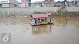 Para siswa SD saat berada di perahu eretan untuk berangkat ke sekolah di Sungai Ciliwung, Jakarta, Senin, (4/1). Usai libur panjang para siswa kembali beraktivitas mengikuti tahun ajaran 2016-2017. (Liputan6.com/Gempur M Surya)