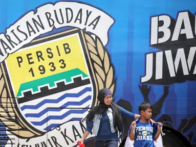 Pendukung Persib berjalan di samping Bus Bandung Tour on Bus (Bandros) yang akan mengangkut para pemain Persib Bandung dalam Pawai Persib Juara Piala Presiden di Kota Baru Parahyangan, Bandung, Minggu (25/10/2015). (Bola.com/Nick Hanoatubun)