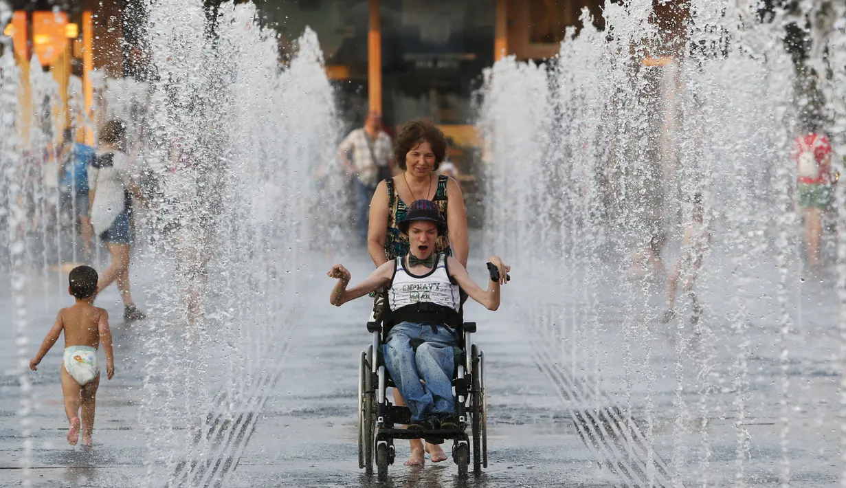 Warga bermain diantara air mancur saat menikmati musim panas di taman Gorky, Moskow, Rusia, Minggu (9/8/2015). (REUTERS/Sergei Karpukhin)