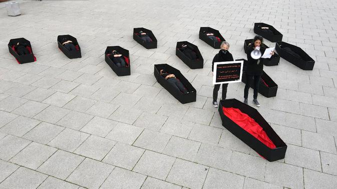 Para wanita berbaring dalam peti mati tiruan untuk mewakili mereka yang tewas akibat kekerasan dalam rumah tangga jelang Hari Perempuan Internasional di luar Pengadilan Distrik, Tel Aviv, Israel, Minggu (7/3/2021). Hari Perempuan Internasional dirayakan setiap tanggal 8 Maret. (JACK GUEZ/AFP)