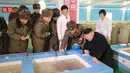 Pemimpin Korea Utara, Kim Jong Un melihat tempat pembibitan ikan lele di Samchon Catfish Farm, Korea Utara, Selasa (21/2). Wajah Kim Jong Un terlihat bahagia saat melihat bibit-bibit ikan lele. (AFP Photo/KCNA)