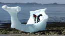 Anak-anak bermain di bongkahan es berukuran raksasa di Nuuk, Greenland, 5 Juni 2016. Bongkahan es tersebut berasal dari gunung es yang mancair akibat cuaca panas terus-menerus di Greenland. (REUTERS / Alister Doyle)