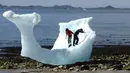 Anak-anak bermain di bongkahan es berukuran raksasa di Nuuk, Greenland, 5 Juni 2016. Bongkahan es tersebut berasal dari gunung es yang mancair akibat cuaca panas terus-menerus di Greenland. (REUTERS / Alister Doyle)